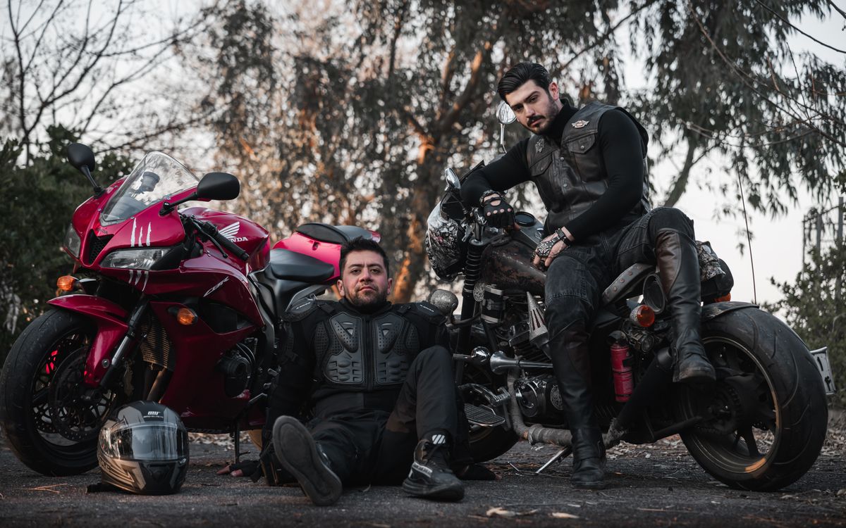 Des motards en cuir posant près d'une moto classique