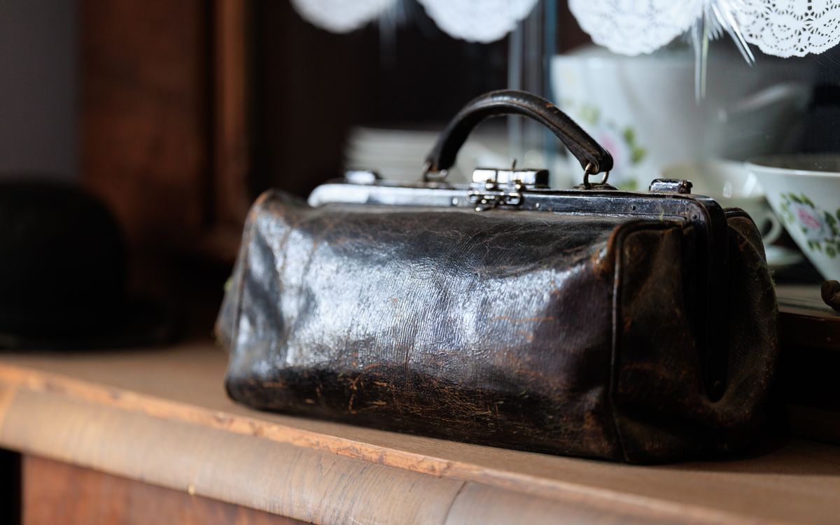 Un sac en cuir vintage posé sur une étagère en bois, riche de patine