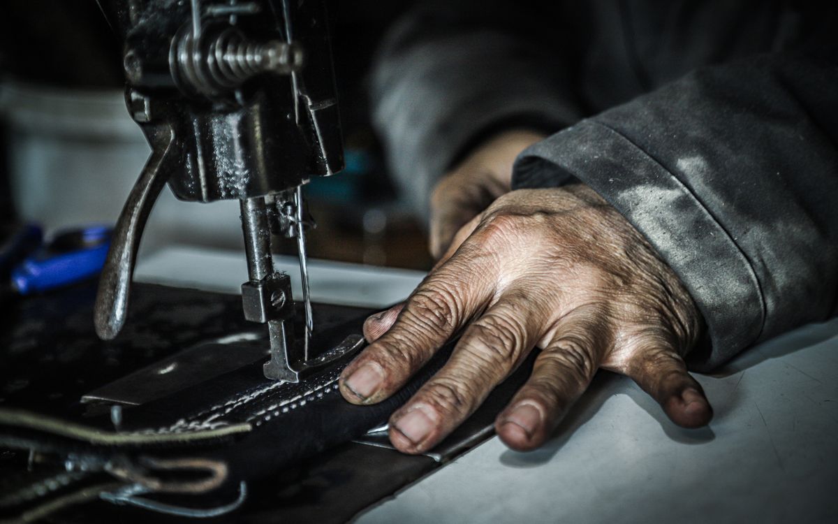Mains guidant la matiere sous une machine a coudre dans un atelier