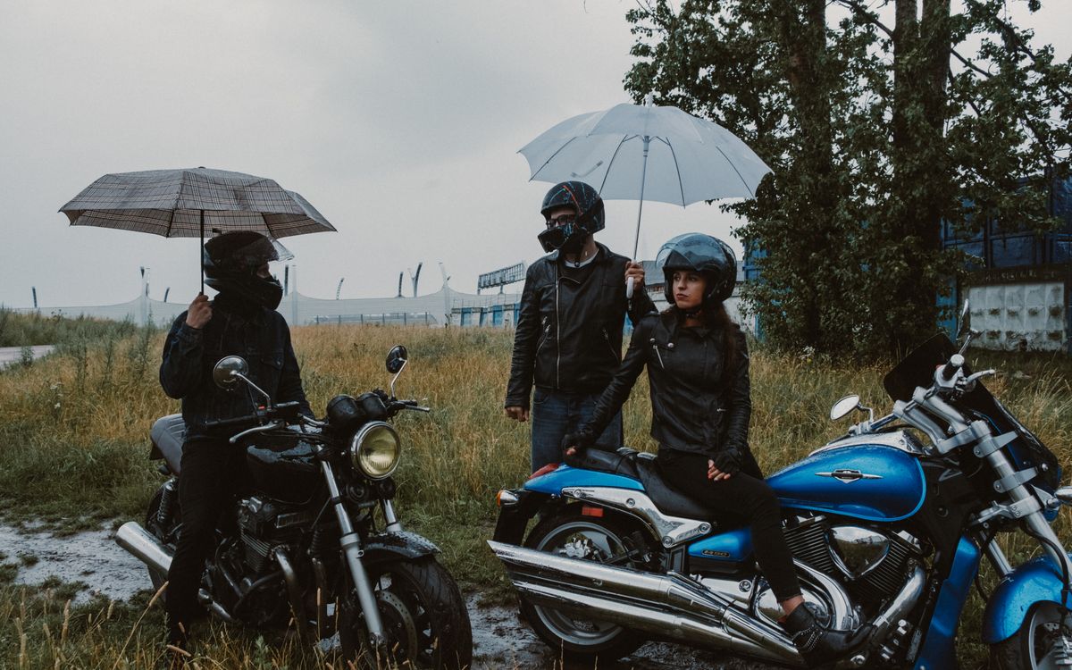 Motards s'abritant de la pluie sous des parapluies dans un champ