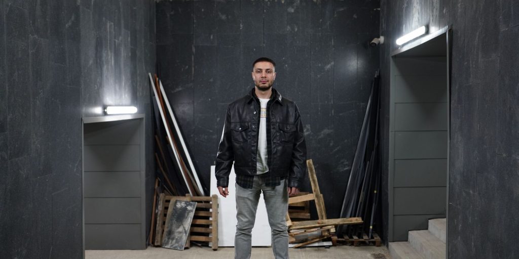 Homme confiant portant une veste en cuir noire dans un espace industriel