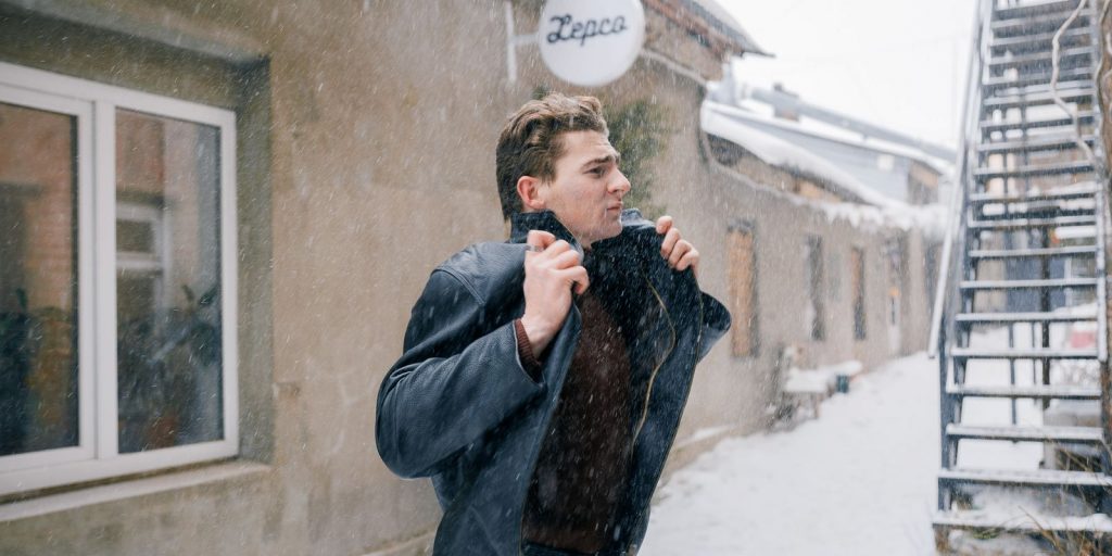 Homme marchant dehors en hiver et remontant son col contre le froid