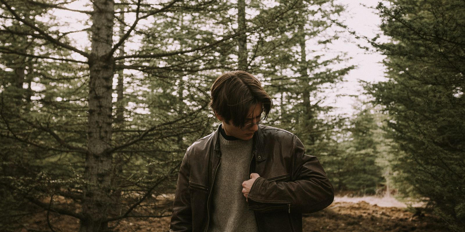 Homme portant un blouson en cuir dans un cadre forestier paisible