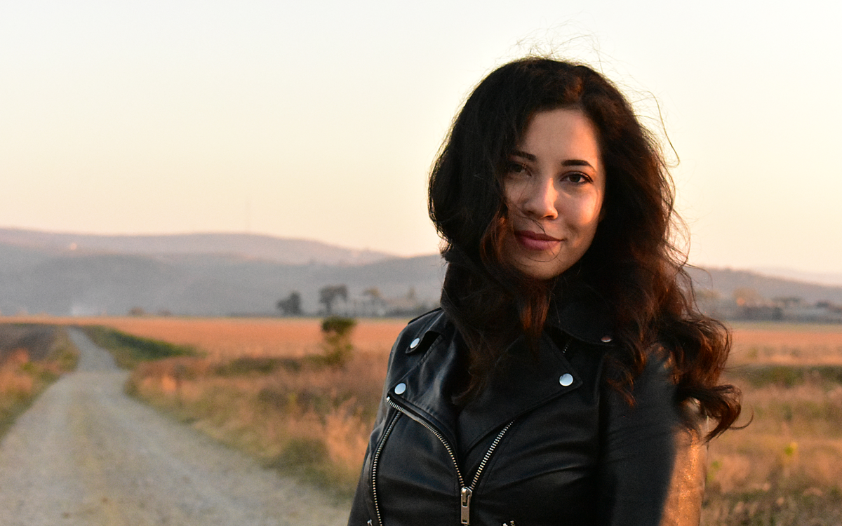 Femme en blouson en cuir noir sur une route de campagne au coucher du soleil