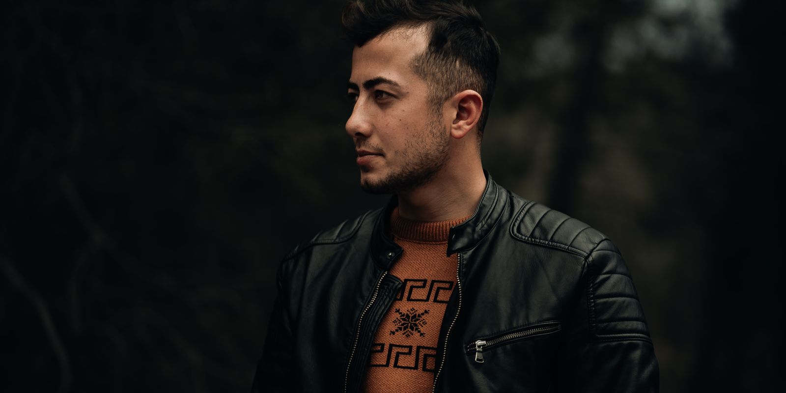 Portrait de profil d'un homme en blouson de cuir noir sur fond sombre