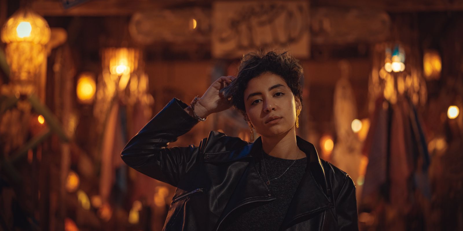 Femme en veste de cuir noire dehors, dans la lumière naturelle du soir