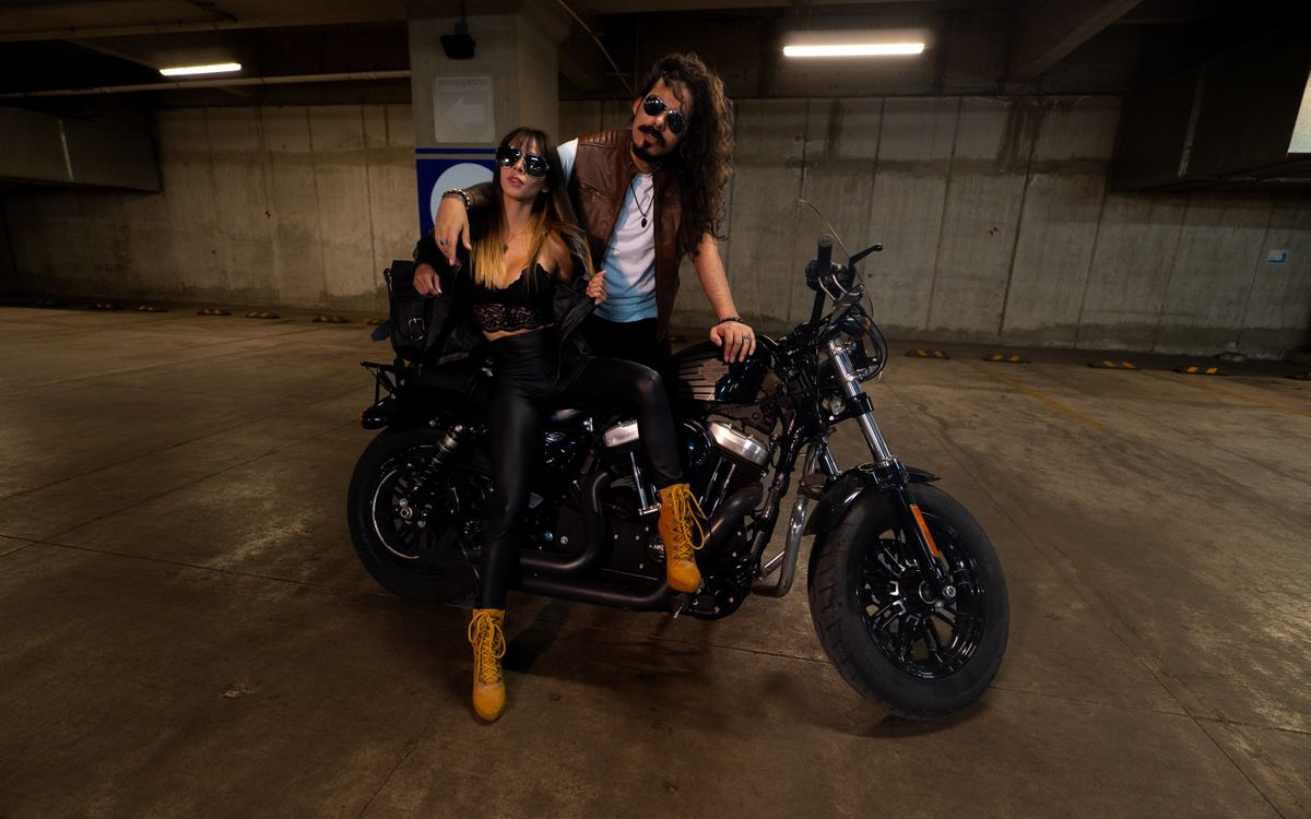 Couple élégant en tenues de cuir posant avec une moto dans un garage