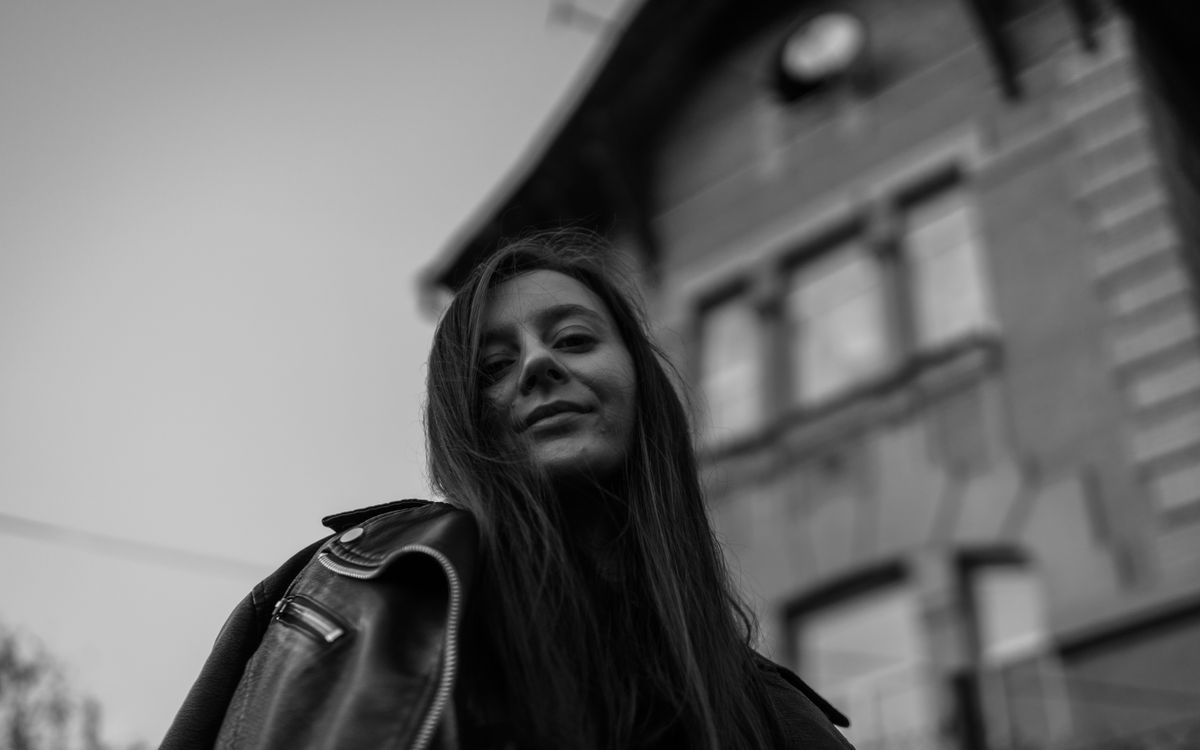 Une femme souriante en veste en cuir en extérieur, portrait en noir et blanc