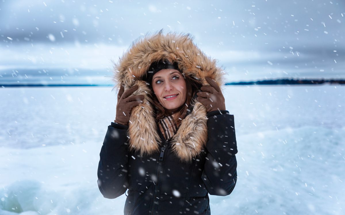 Une femme en manteau garni de fourrure dehors sous la neige