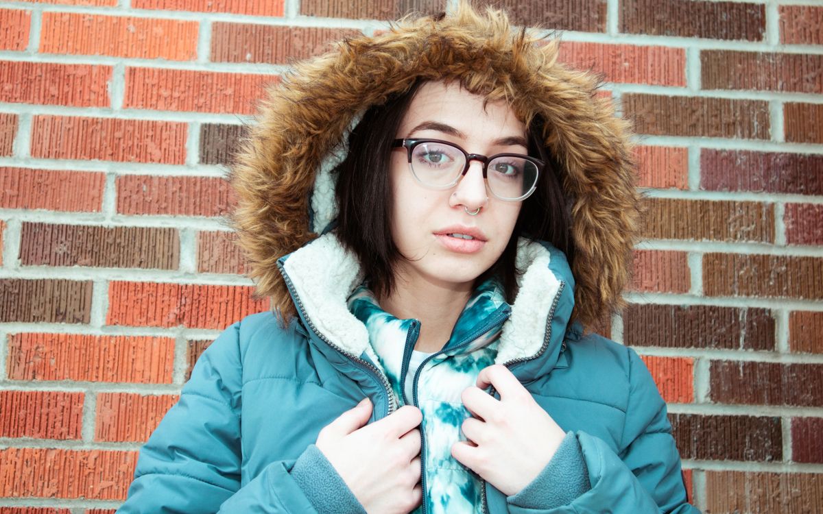 Portrait d'une femme avec des lunettes et une veste garnie de fourrure