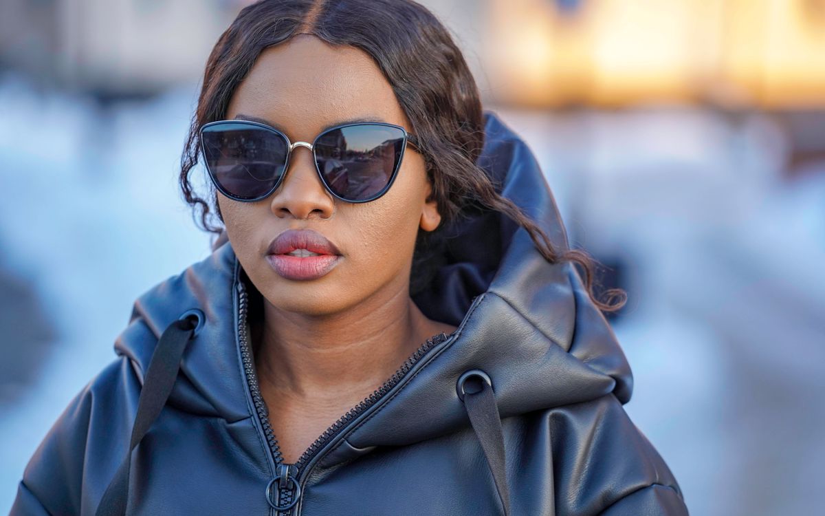 Une femme en lunettes de soleil et veste de cuir noire sur un fond doux