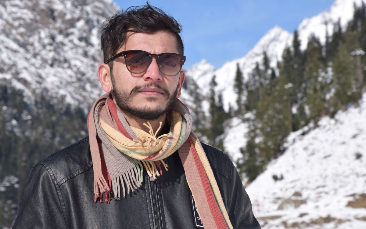 Un homme en écharpe devant des montagnes enneigées par une journée froide et claire