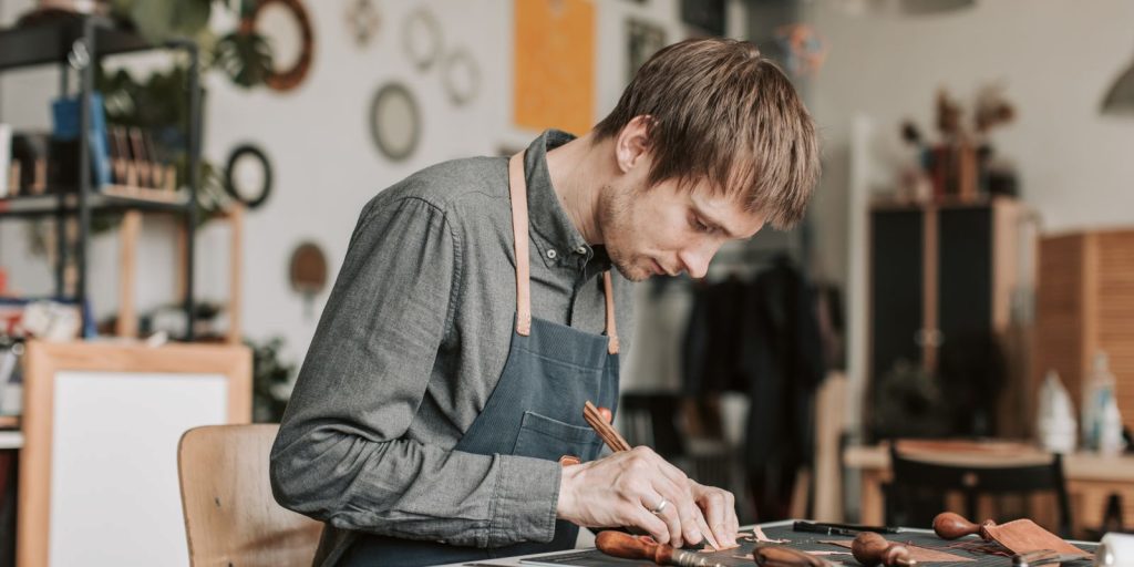 Un artisan qualifié travaillant le cuir à la main sur sa table d'atelier