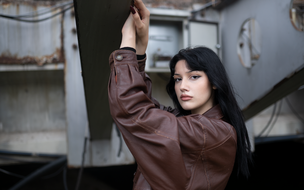 Une jeune femme portant un blouson en cuir marron avec une expression sûre d'elle