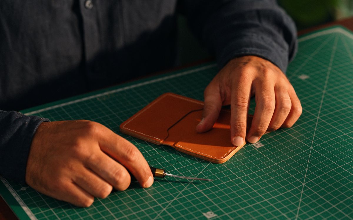 Gros plan sur des mains façonnant une pièce de cuir sur un établi