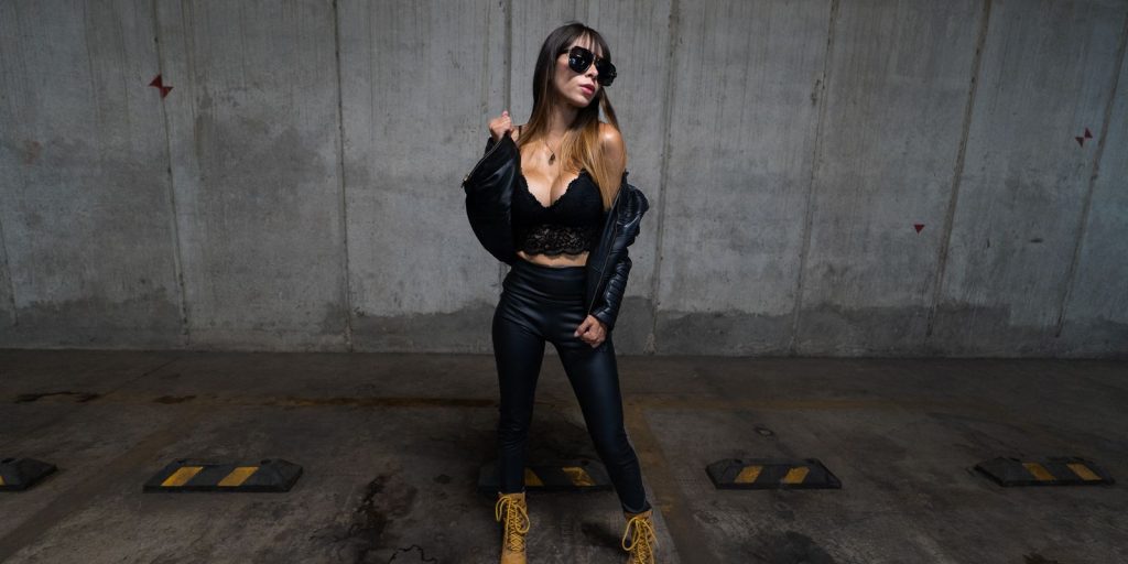 Une femme élégante en veste de cuir noire pose avec assurance dans une rue urbaine